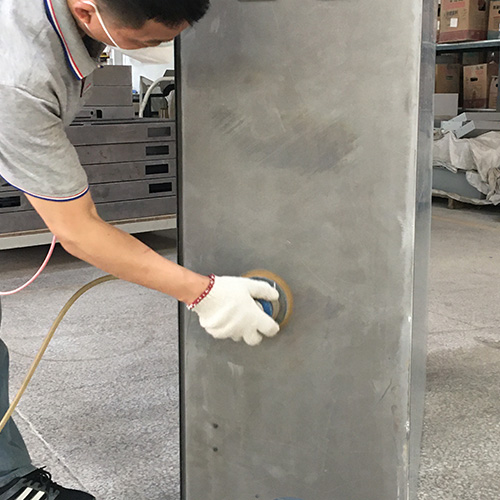 Worker grinding welds and smoothing a metal electrical enclosure