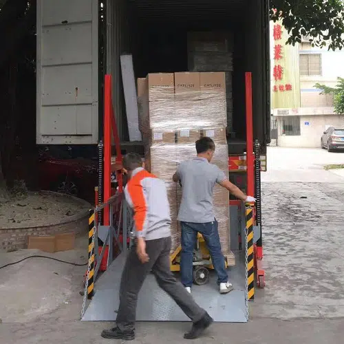 Workers loading packaged electrical enclosures into a freight container